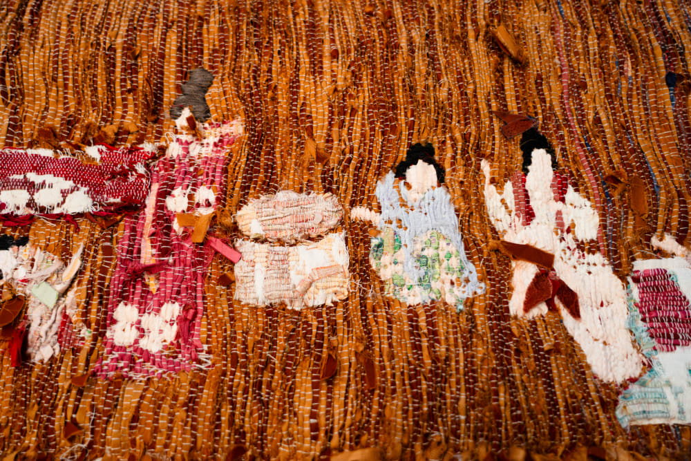 Image shows an orange piece of ribbed fabric with intricate embroidery 