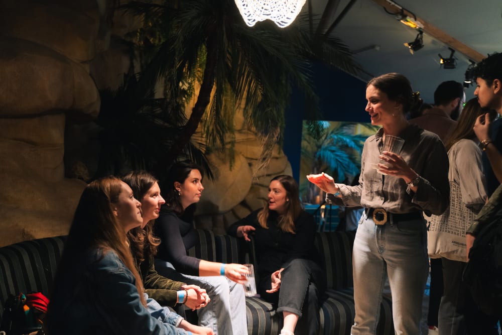 A guest is standing up, chatting to a group sitting down. 