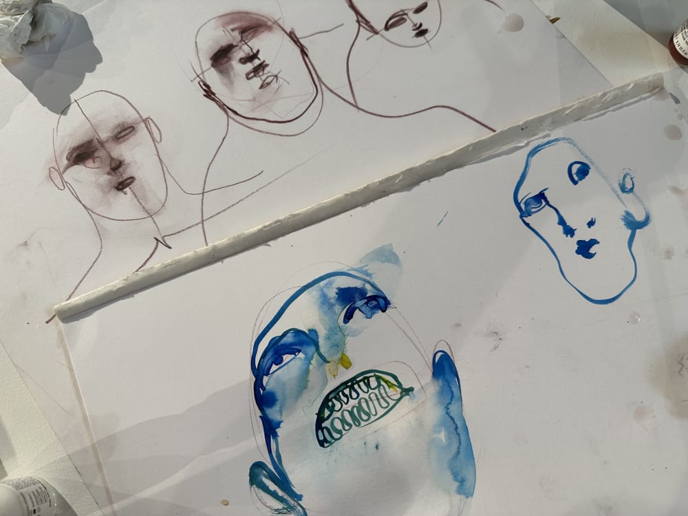 Two pieces of paper with faces sketched on.