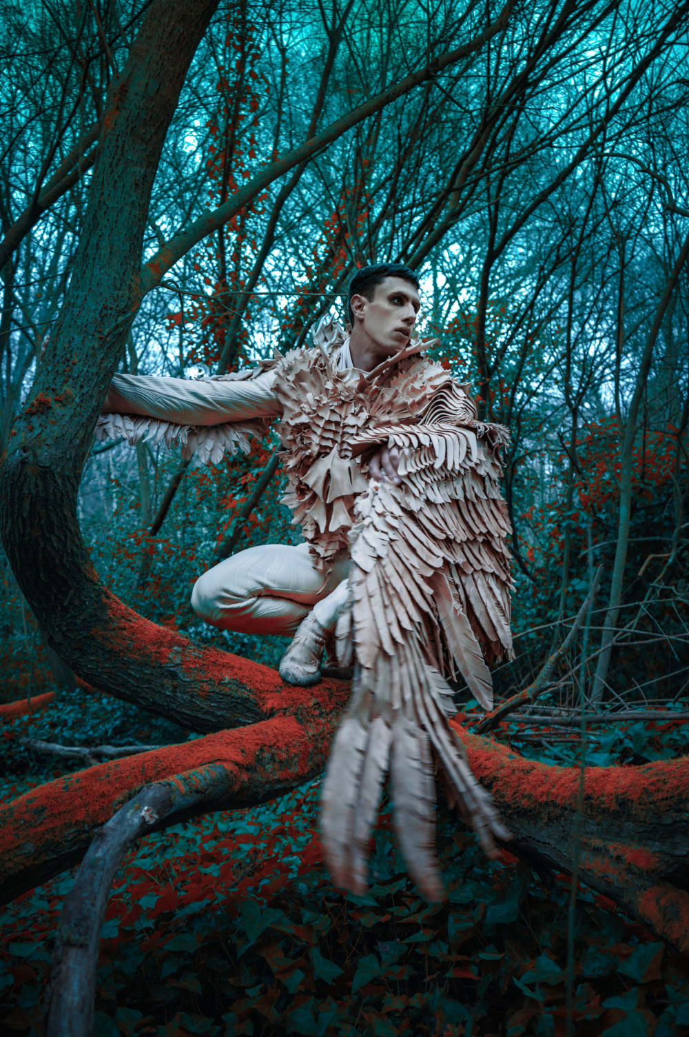 man in bird like costume posing in trees