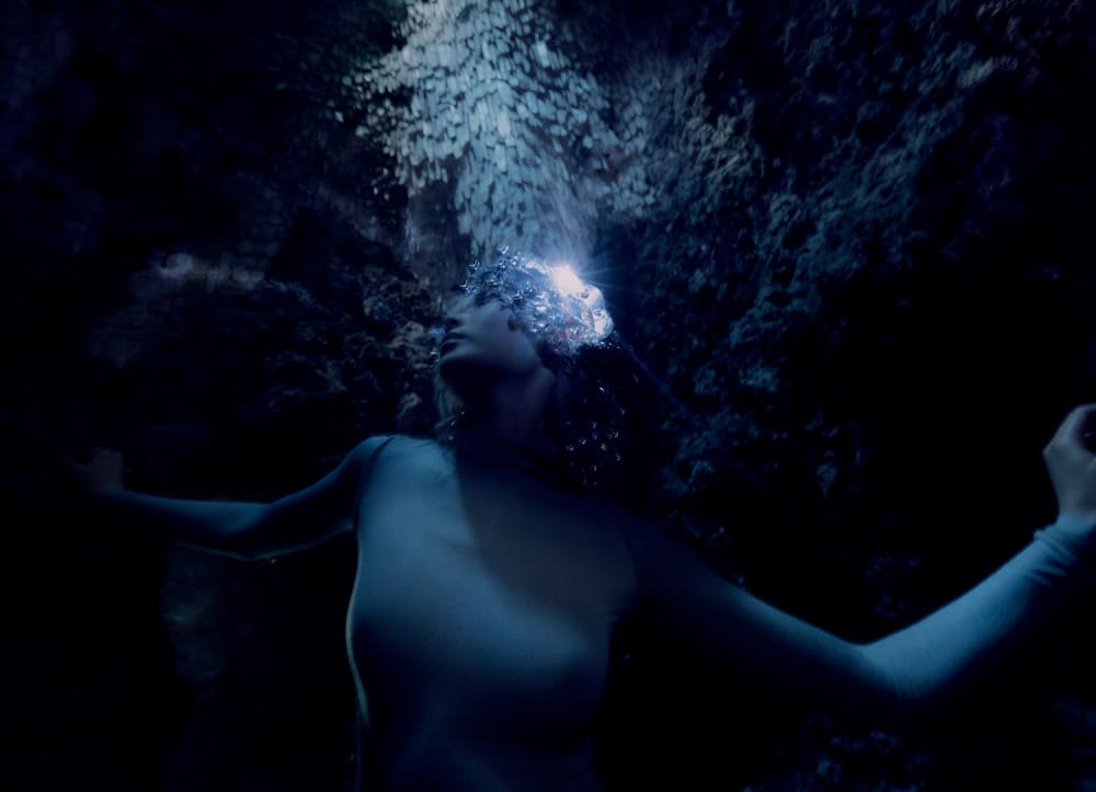  This image reimagines Zhang Shun with a female model in fish-scale-like attire against a cave-like backdrop.