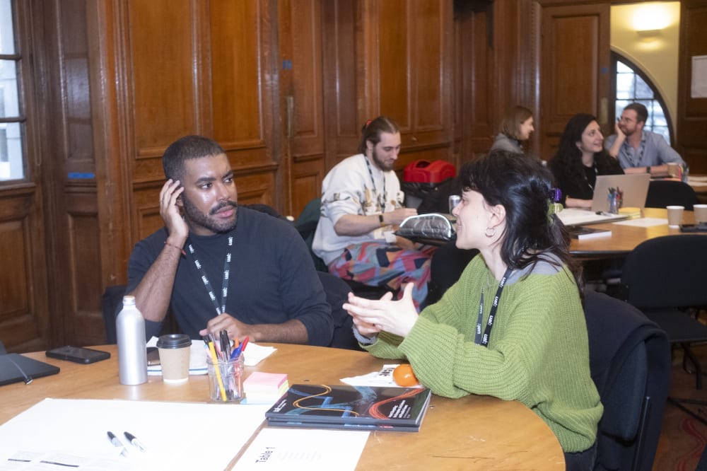 Two people sitting at a table mid discussion.
