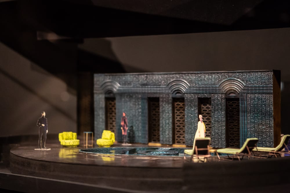 A small scale model of a stage, featuring three people and two chairs