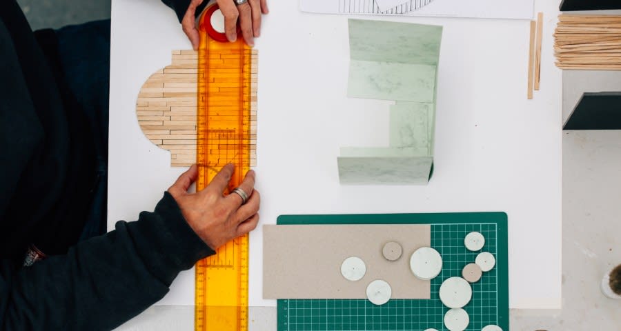 Student cutting out card materials with a ruler