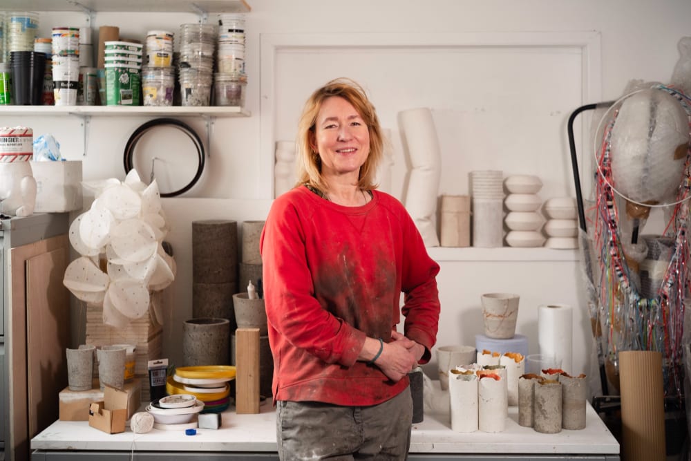 Woman in red jumper smiling to camera, in a workshop