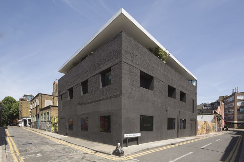 a photo of a large, dark grey house with sharp angles taken from the street