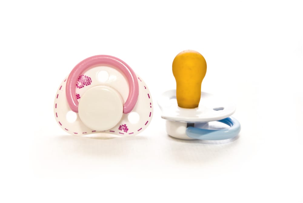 a studio shot of two pacifiers, one pink and one blue