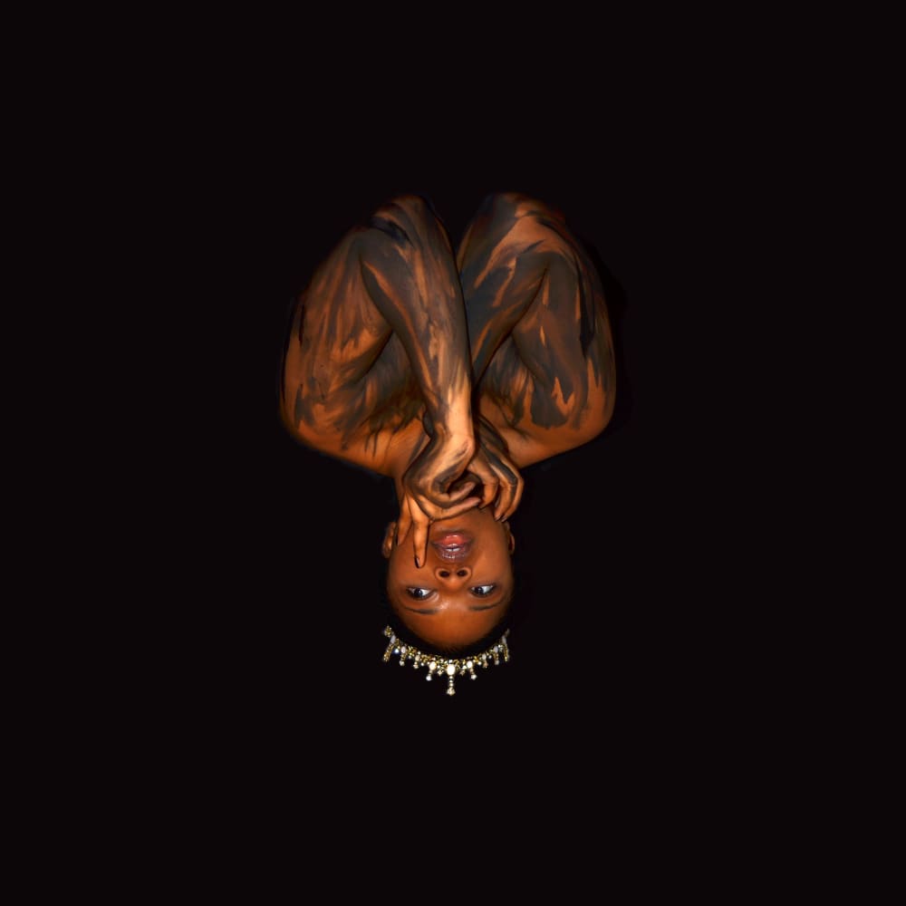 Self-portrait of Savanna, who appears upside down. Savanna is black women wearing a crown, the background is a black.