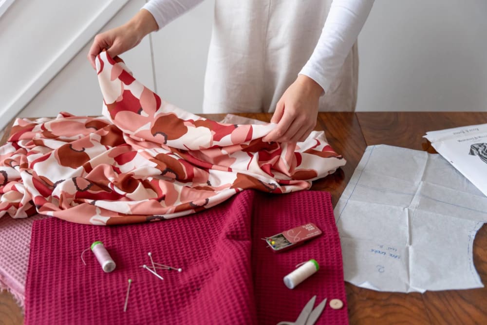 A person stood behind a table, holding patterned material in different shades of pink