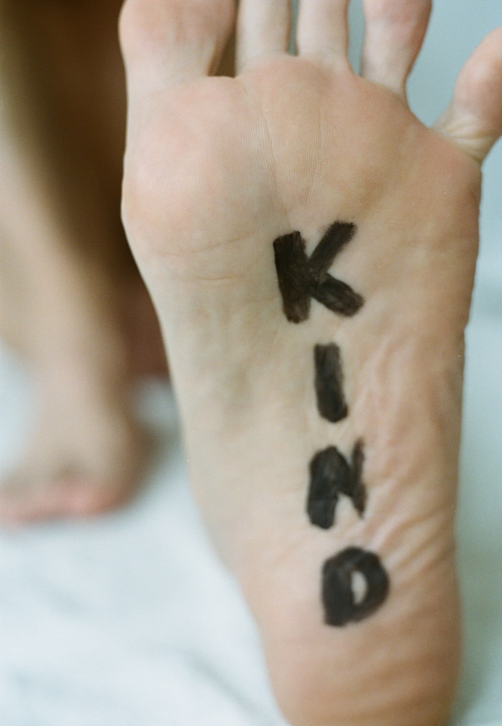 The sole of a foot with Kind written in block capitals down the length