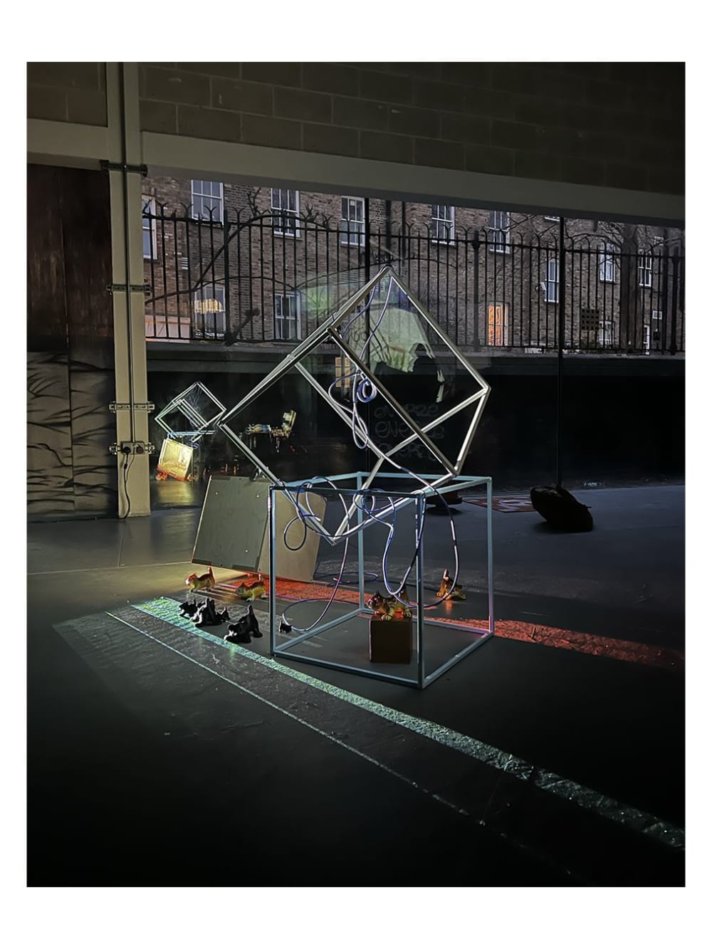 Conceptual structure, made up of two metal cubed structures, draped in wire and surrounded by ceramic tigers. 