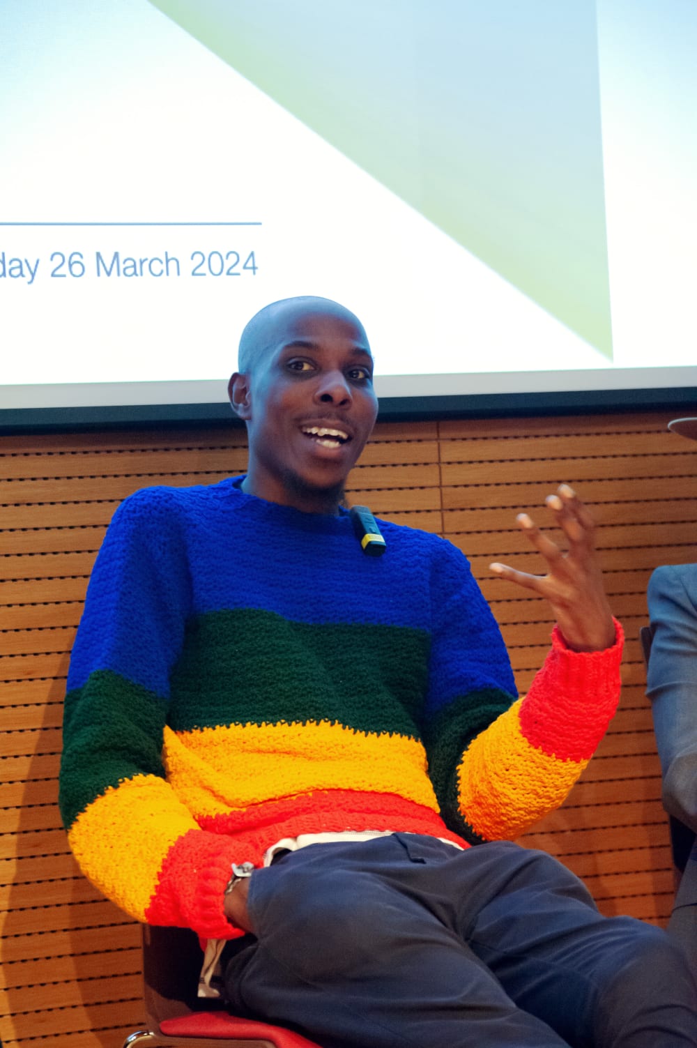 Samuel talking. He's wearing a brightly coloured striped jumper