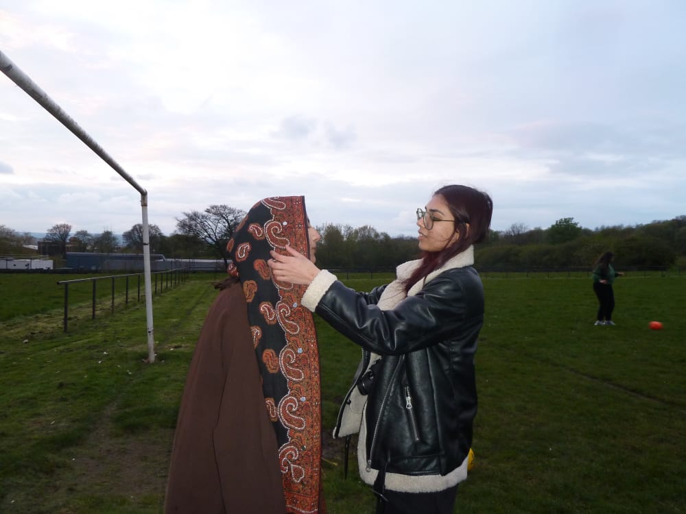 Two women standing on a football field.