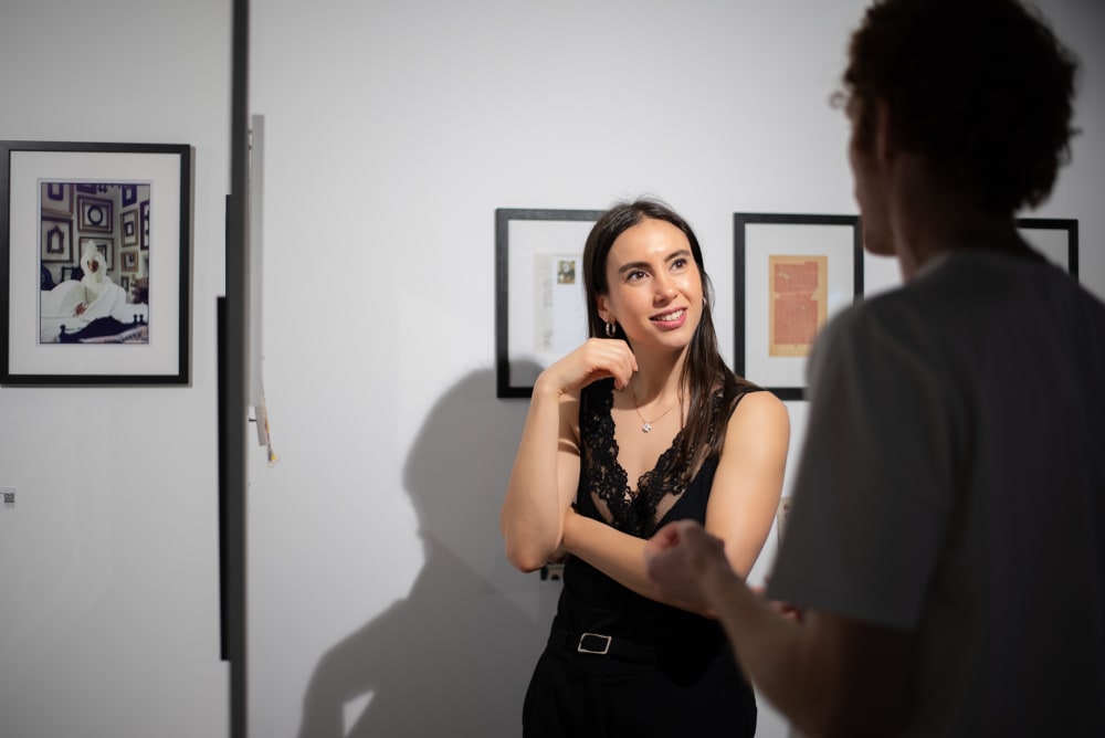 2 visitors standing chatting in front of some art work. 