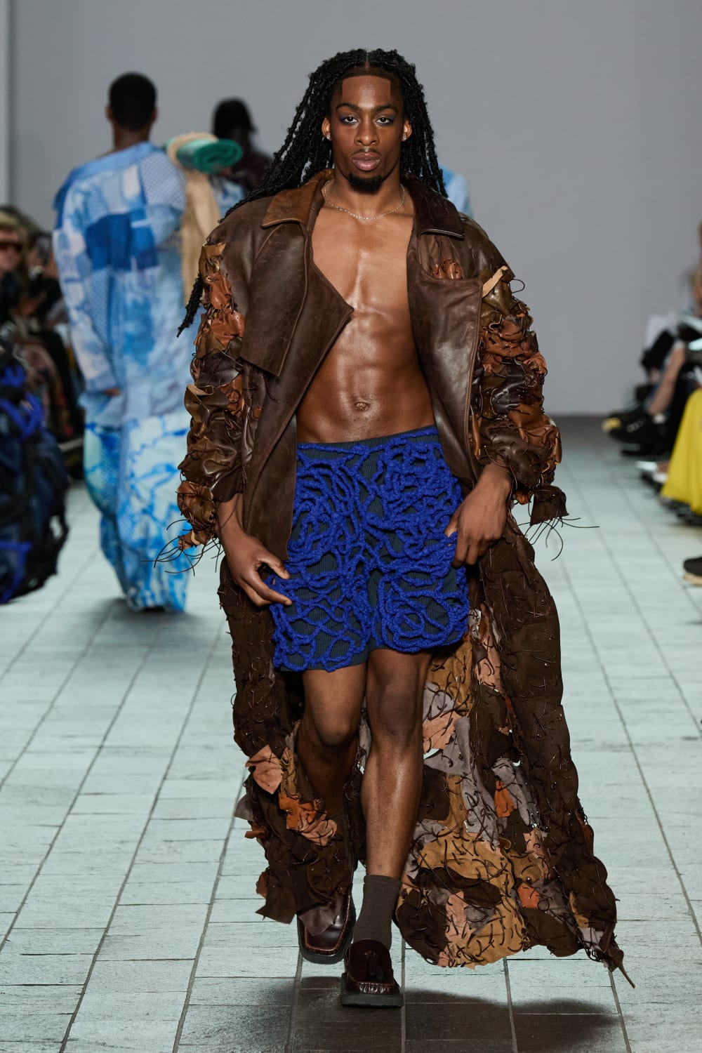 A model wears an electric blue net skirt with a brown leather jacket