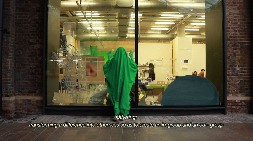 Person covered in green cloth outside shopfront