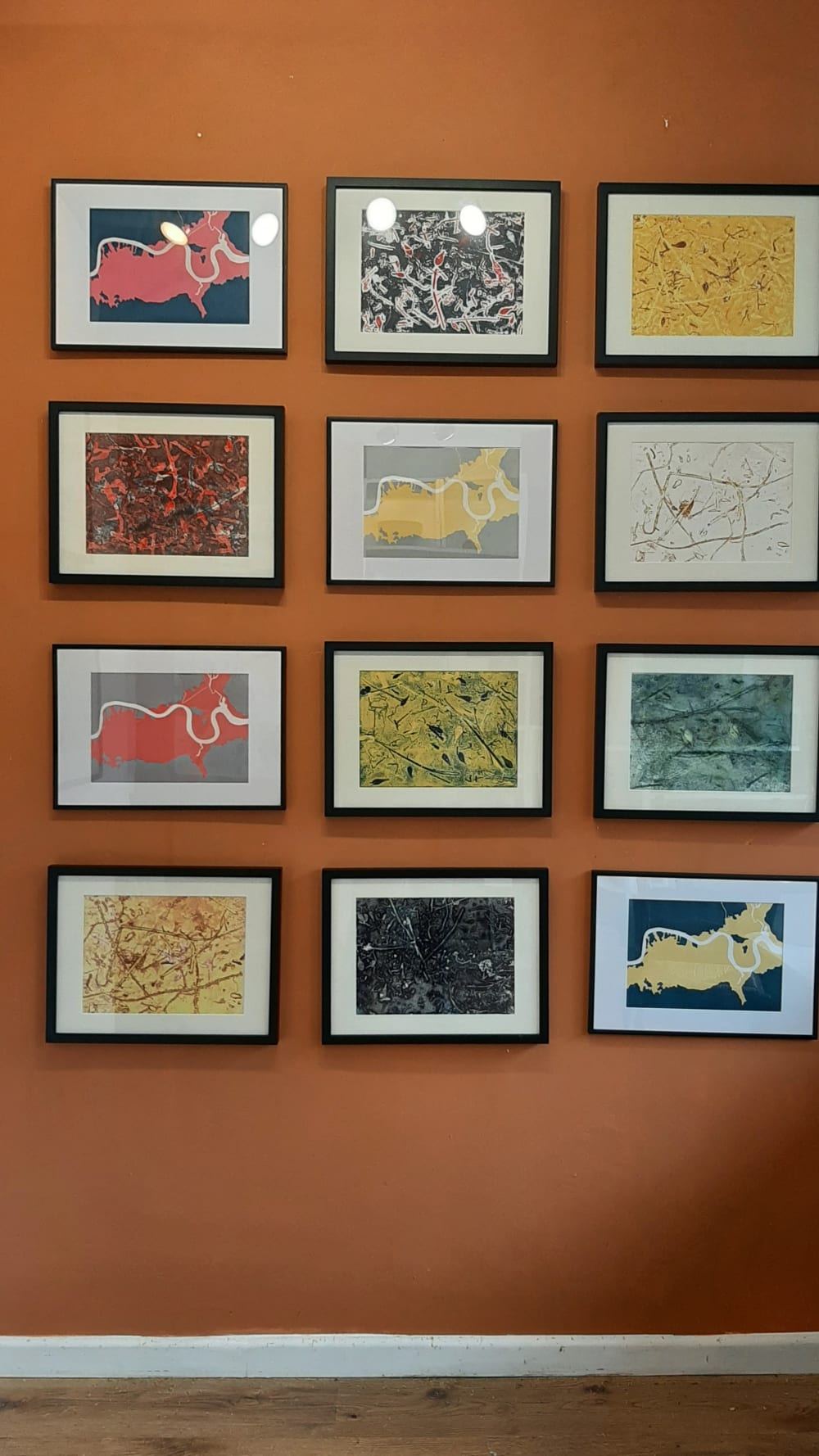 orange wall with 9 framed paintings displayed