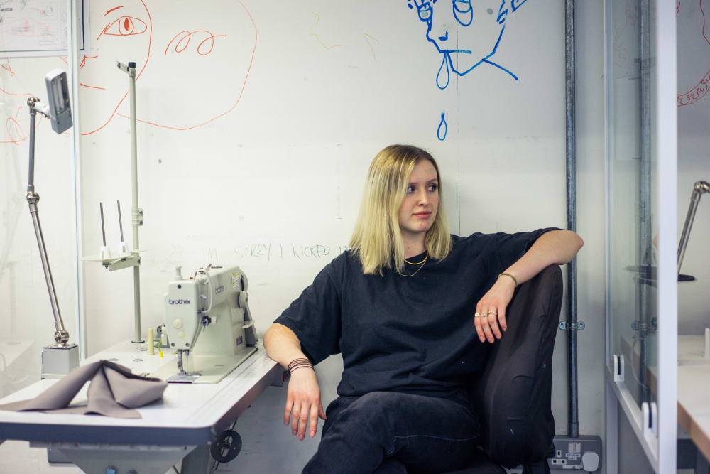 female sitting next to a sewing machine