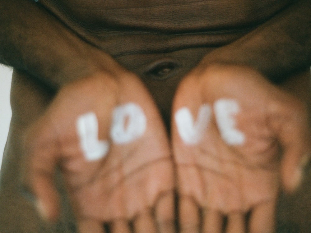 A person's open palms with Love written in block capitals across the centre
