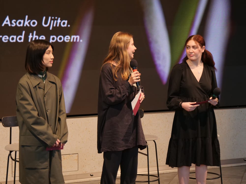 The 3 students presenting on a stage to an audience