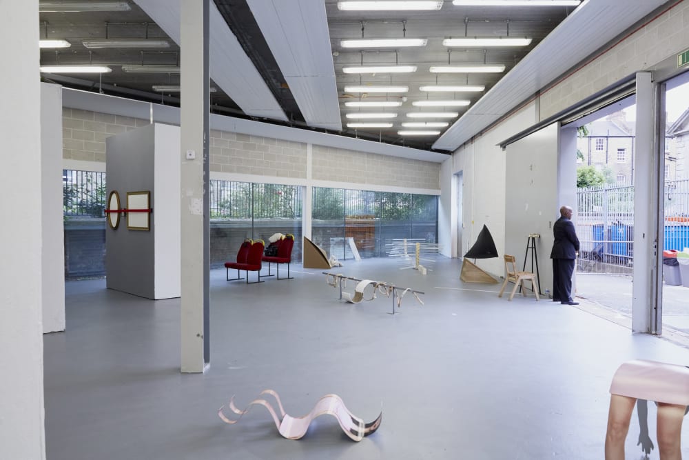 A shot of a room with various pieces of artwork displayed. There is a security guard standing by the door