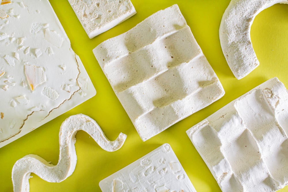 Various textured and shaped art pieces are laid out flat on a table with a bright background