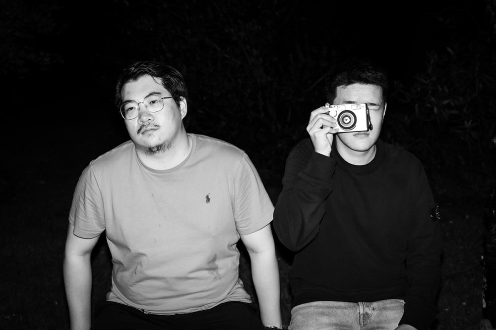 Photograph of two people, one of whom is holding a camera to their face.