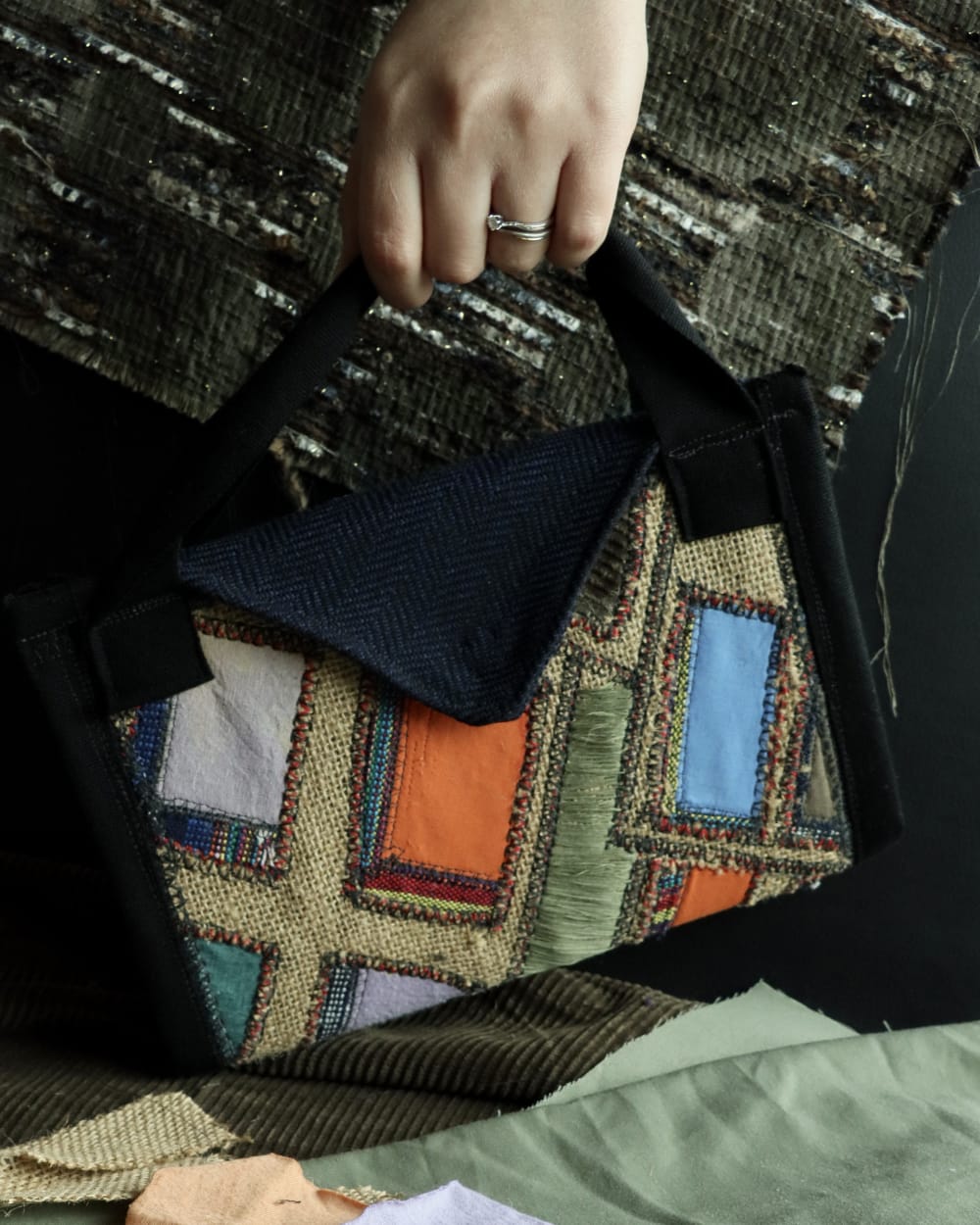 Hand holding a bag made up of scraps of different fabrics in a patchwork pattern
