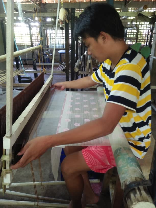a person creating fabric on a loom