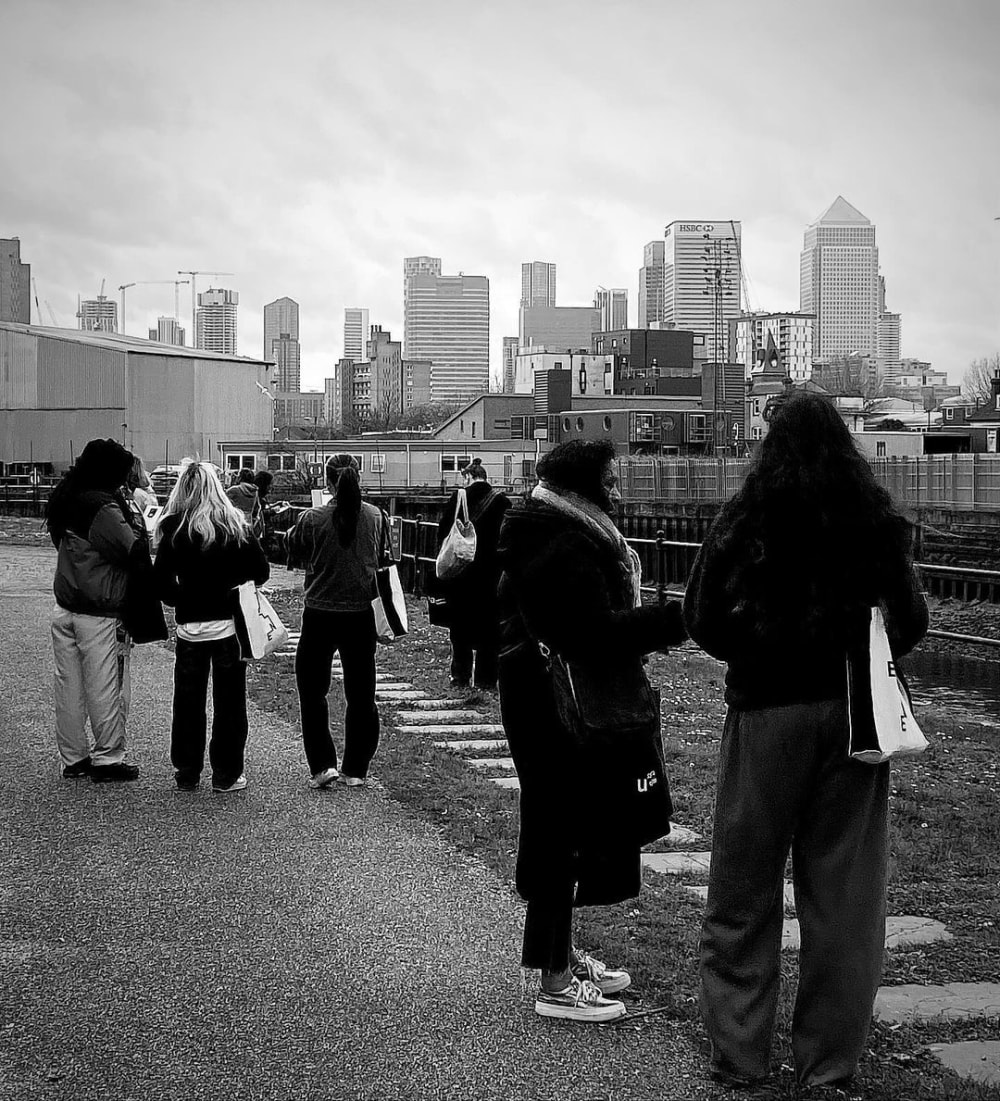 People standing on paved walkway with backdrop of tall buildings behind them.