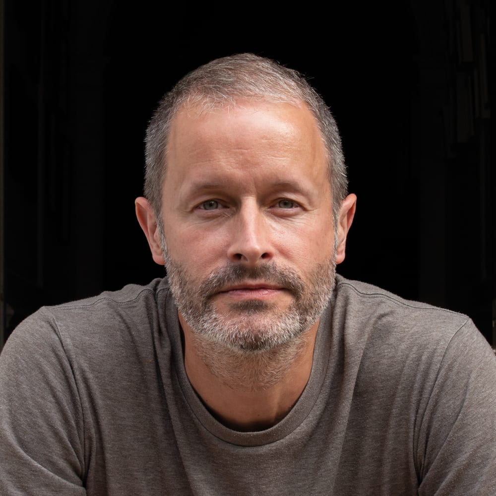 Headshot of Simon. He's wearing a grey top and is looking directly into the camera.