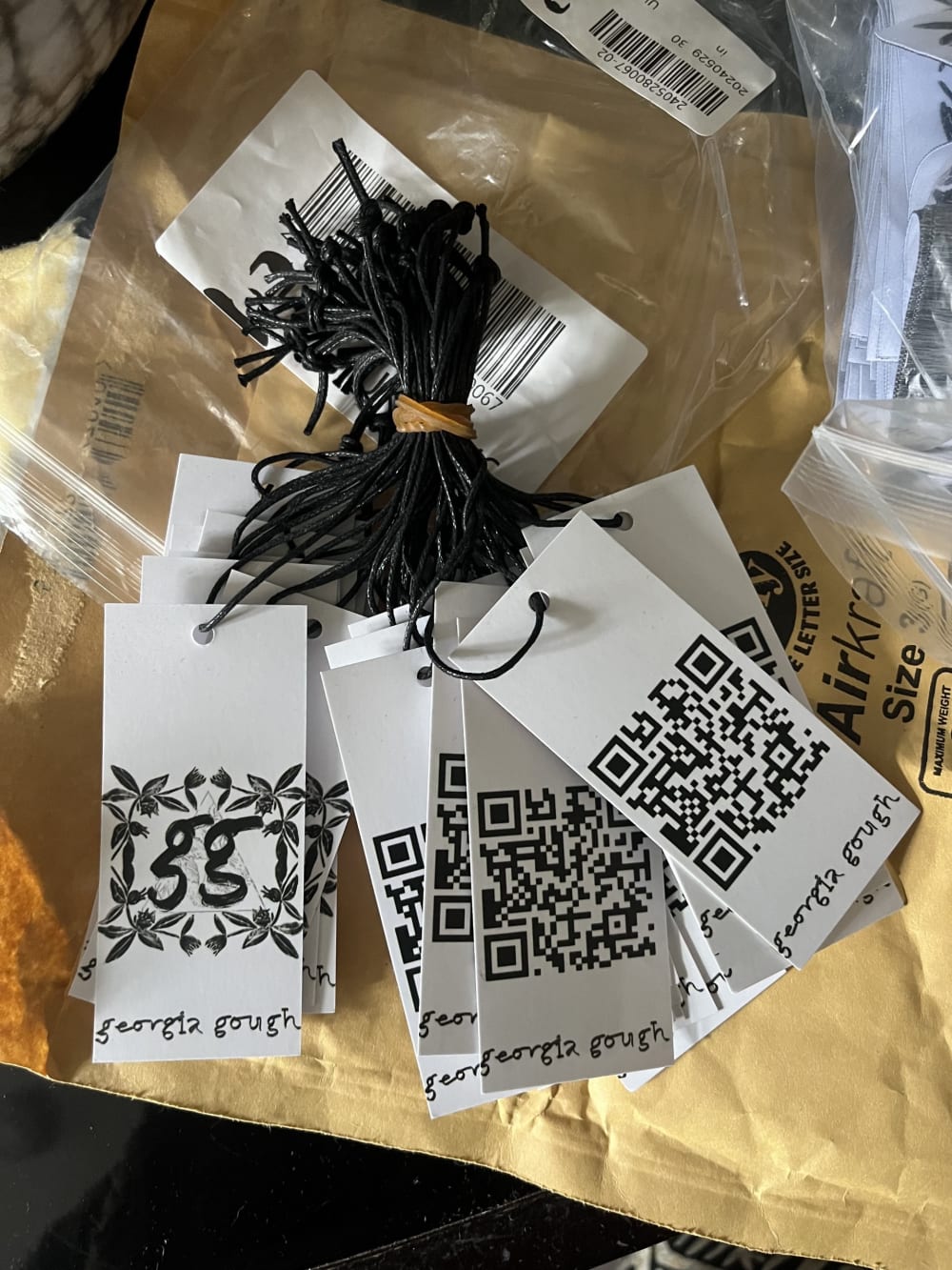 a colection of tags helf together by an elastic band showing a QR code for Georgie Gough