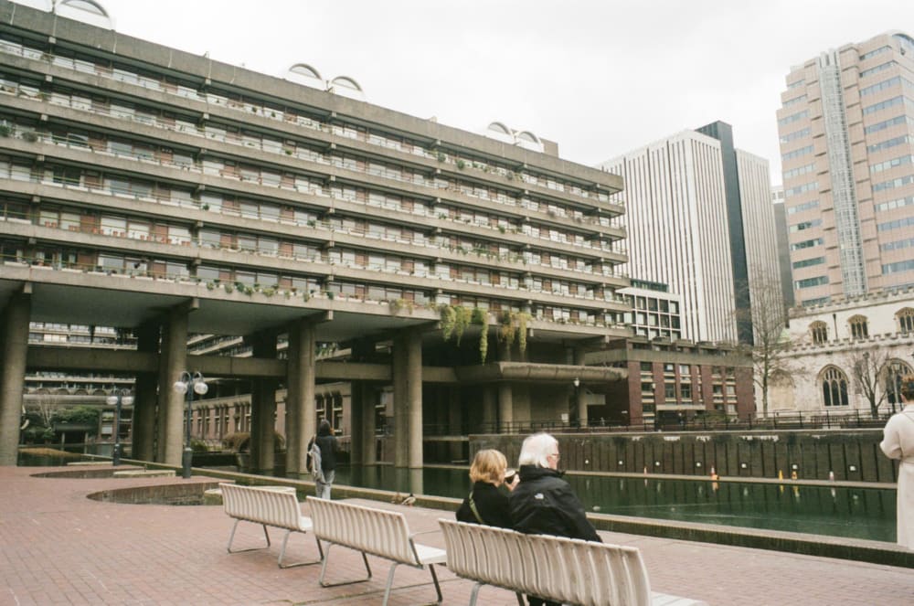 a photo of the barbican estate with two people sat on a bench