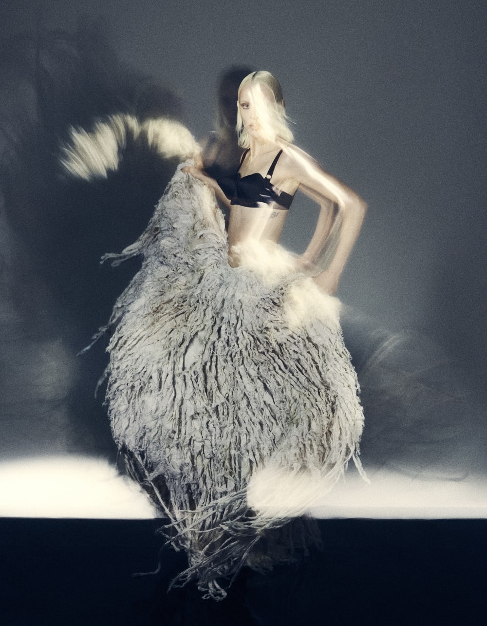 A model wearing a fringe-like long skirt and dancing.