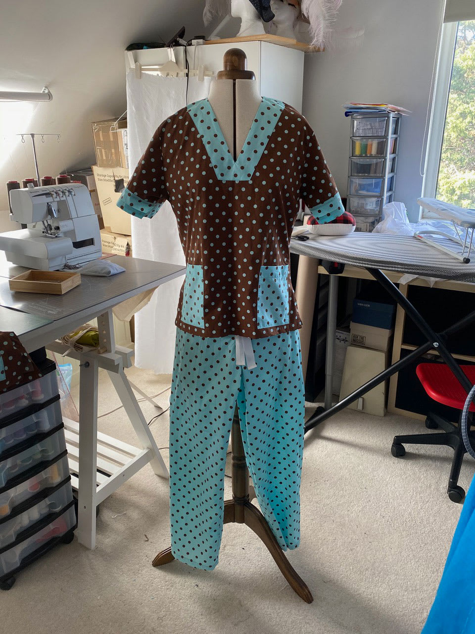 A set of scrubs worn by a mannequin made from brown and blue polkadot fabric.