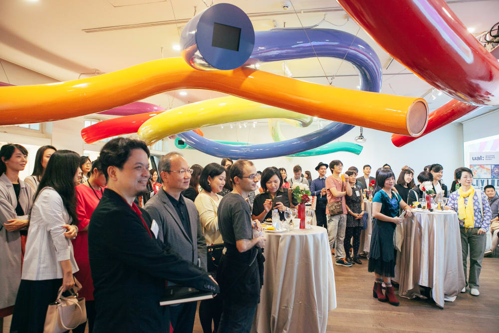 People listening to a presentation under large colourful tubes