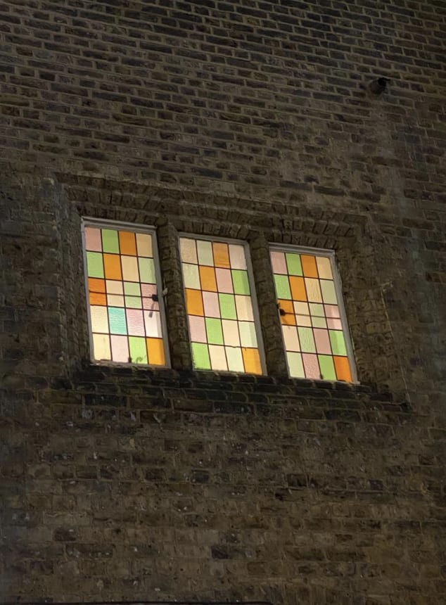 Photograph of the exterior of the college, showing three Victorian stained-glass windows.