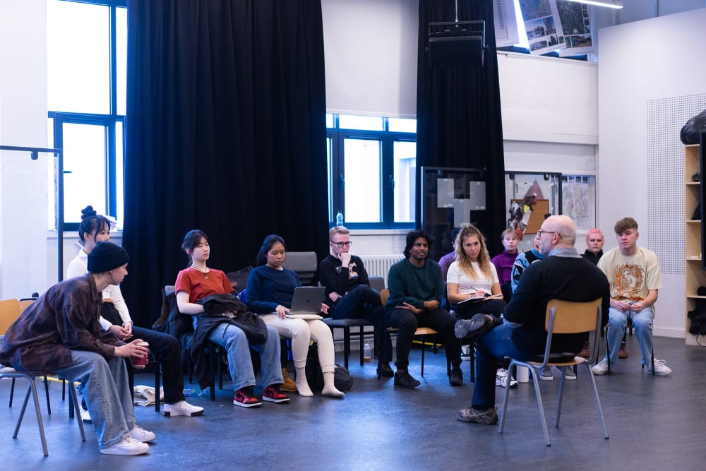12 students sitting down listening to a course tutor