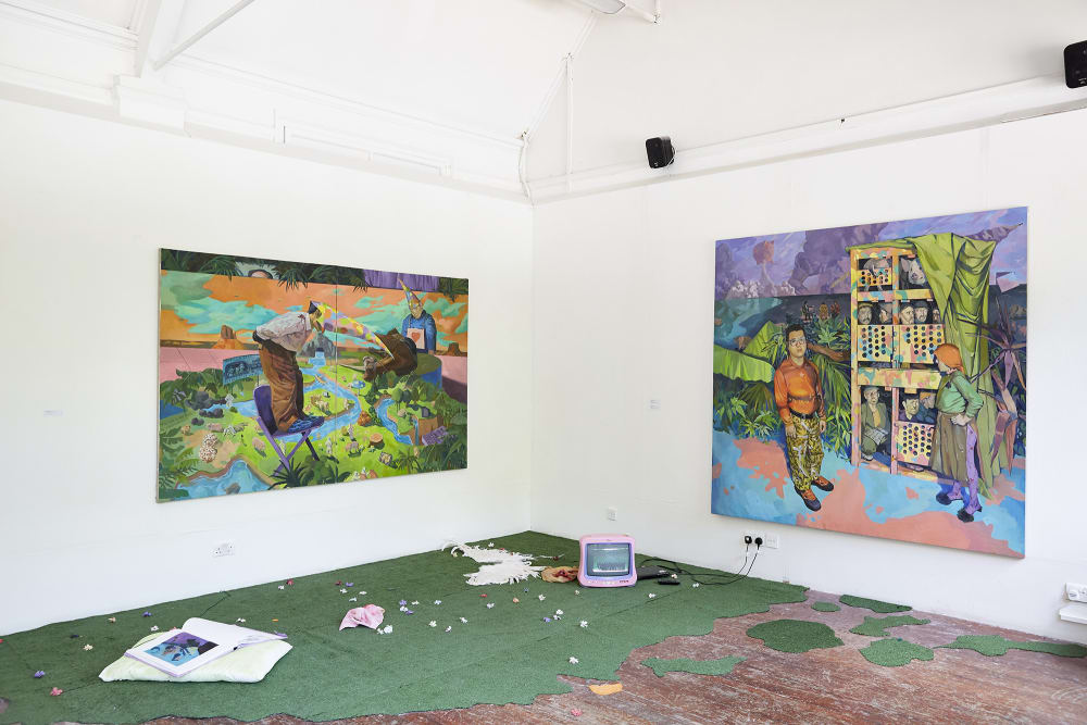 Installation piece, includes two large scale colourful portraits. There is AstroTurf grass partially covering the ground and a small pink TV in the corner.    