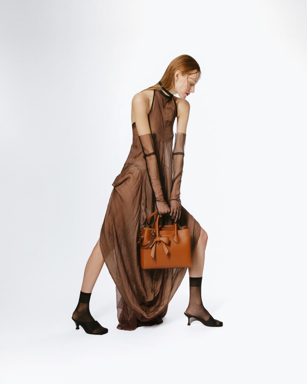 Model with beige clothing and a tanned leather bag