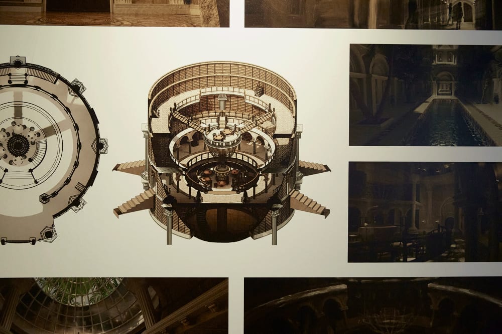 Image shows pieces of paper hanging on the wall detailing designs for a set. The colours used are brown and beige.