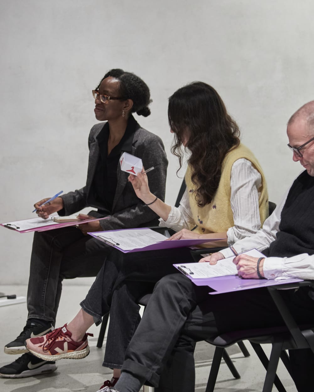 The three jusges sitting in chairs and listening to pitches at the LCF Hack. 