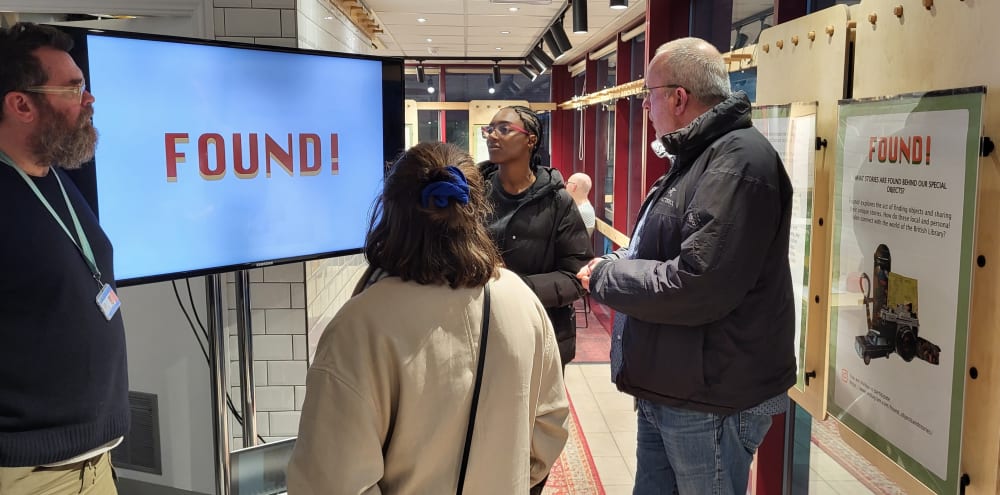 A group of people stood around a screen displaying 'Found!'