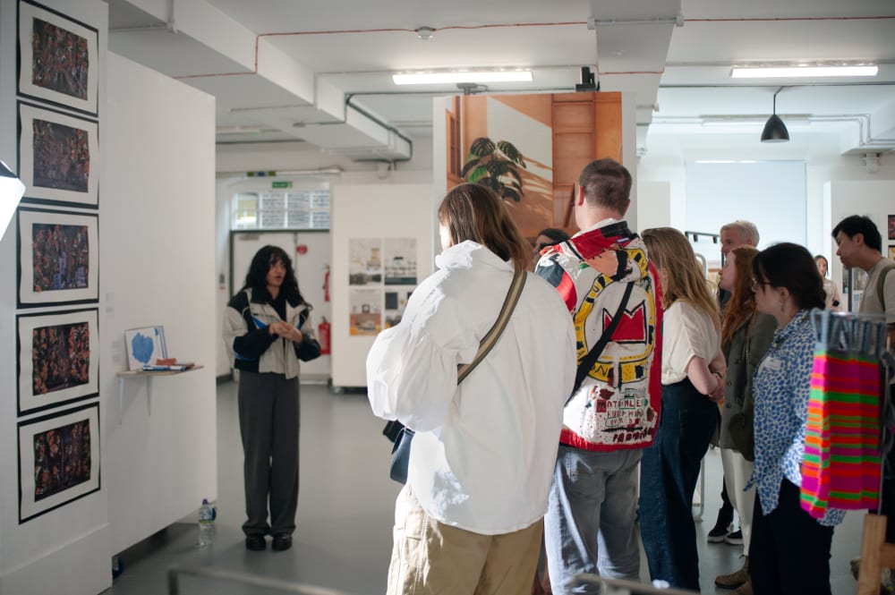 Student explaining her exhibited work to guests at the event