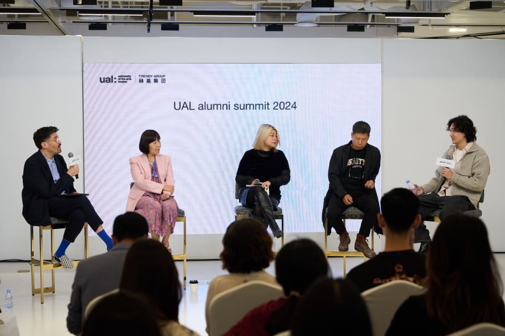 Panel members sitting at the front of the room, talking into microphones