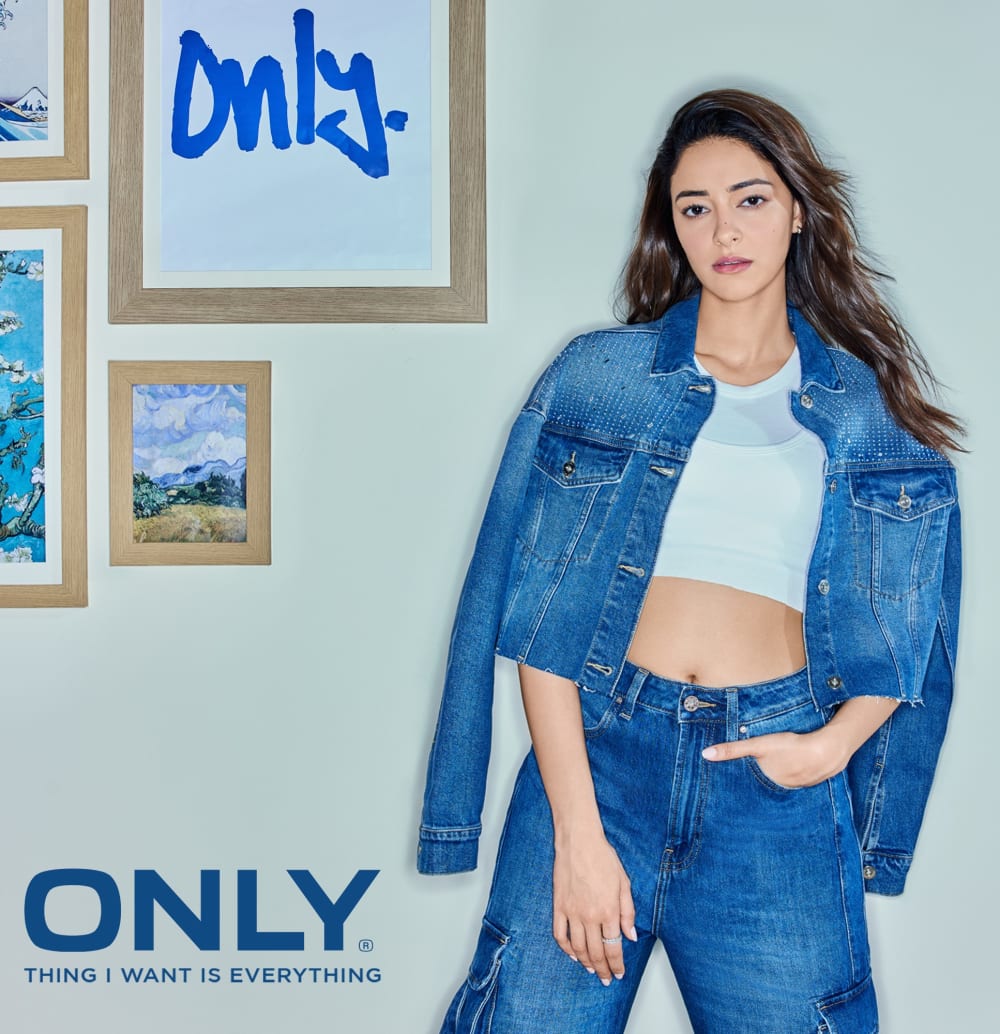 Campaign imagery, with a blue and mint colour palette. There are paintings in frames in the top left corner and a brunette model wearing double denim and a white crop top 