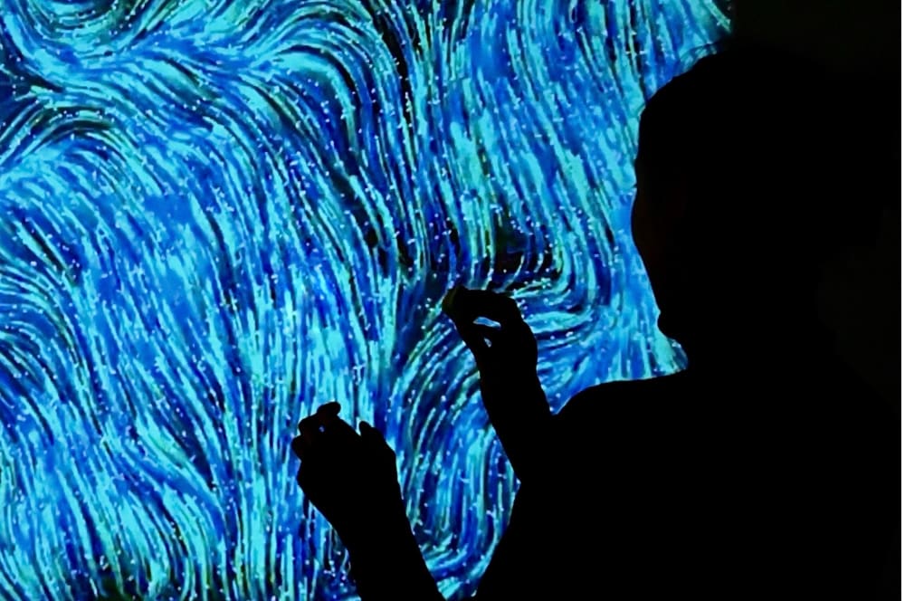 A figure in darkness interacting with a blue swirly artwork