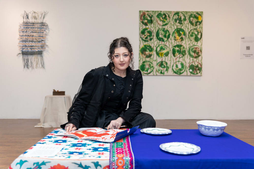 Talbia crouching next to her work on display