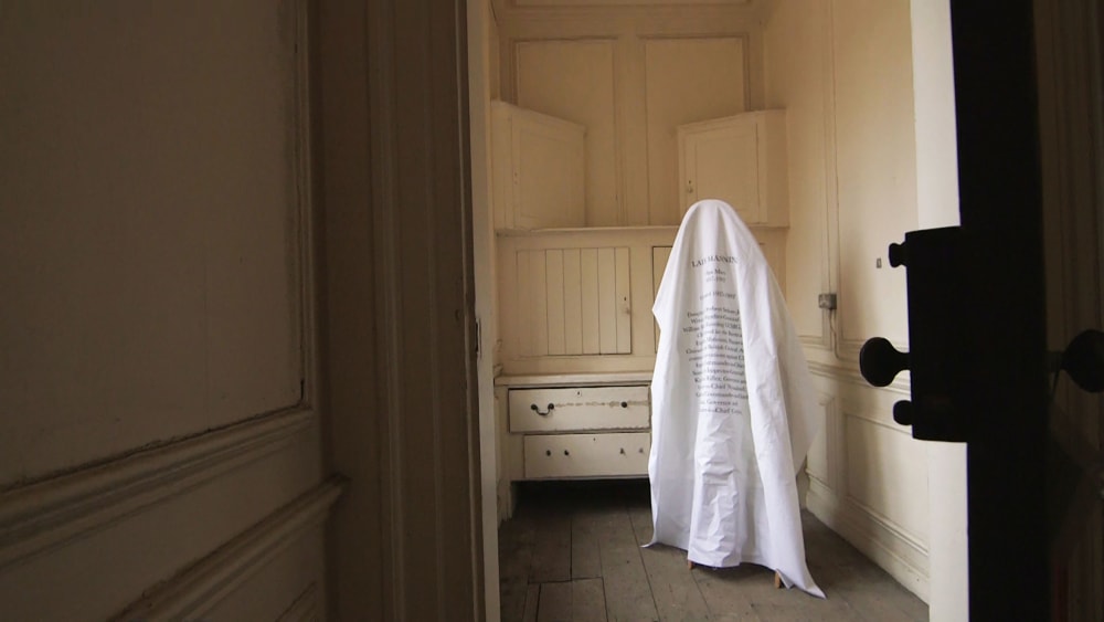 A large piece of material with words written across displayed in an empty room