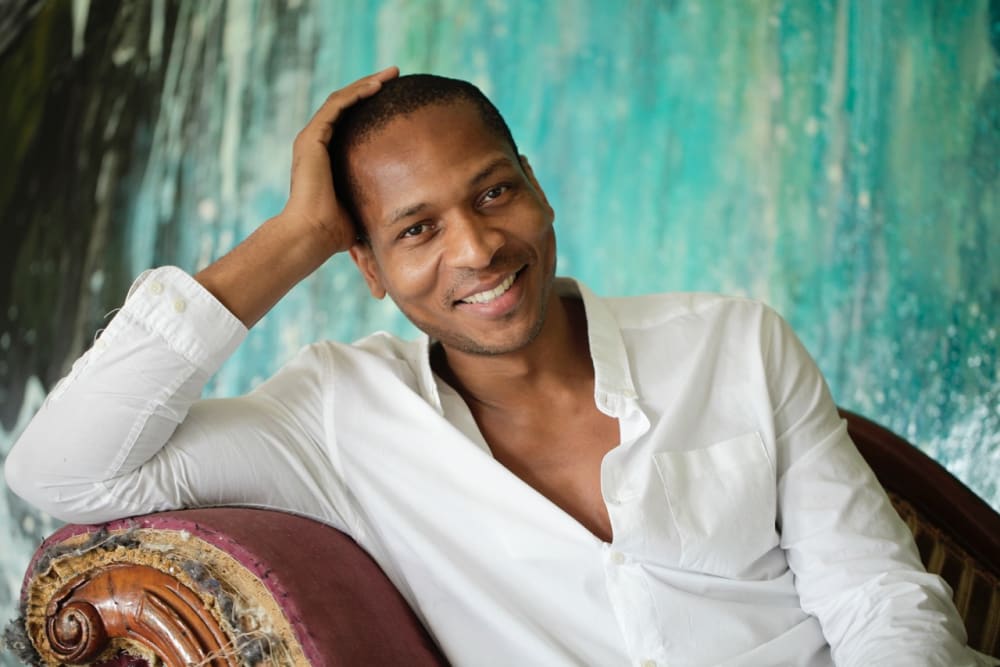 Man reclining on a sofa infront of large green painting